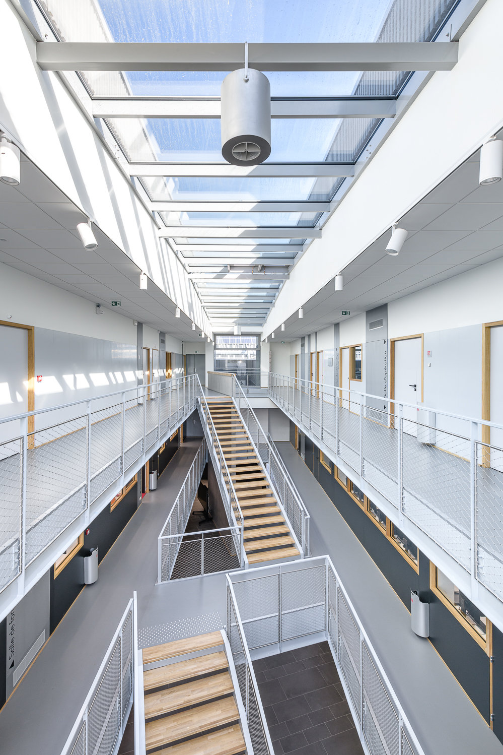 Atrium lumineux d'une école à Bruz, escalier central et passerelles blanches
